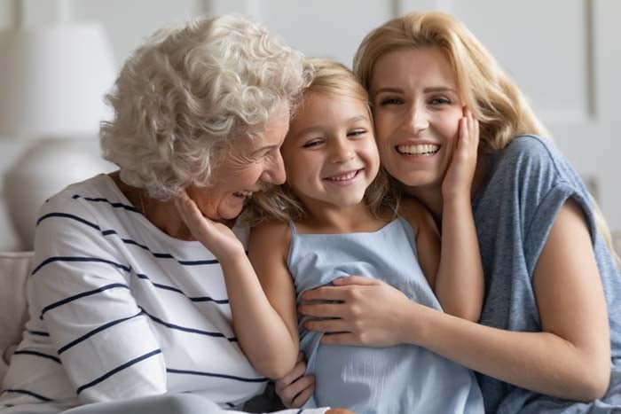 Happy laughing grandmother, mother and little girl embracing